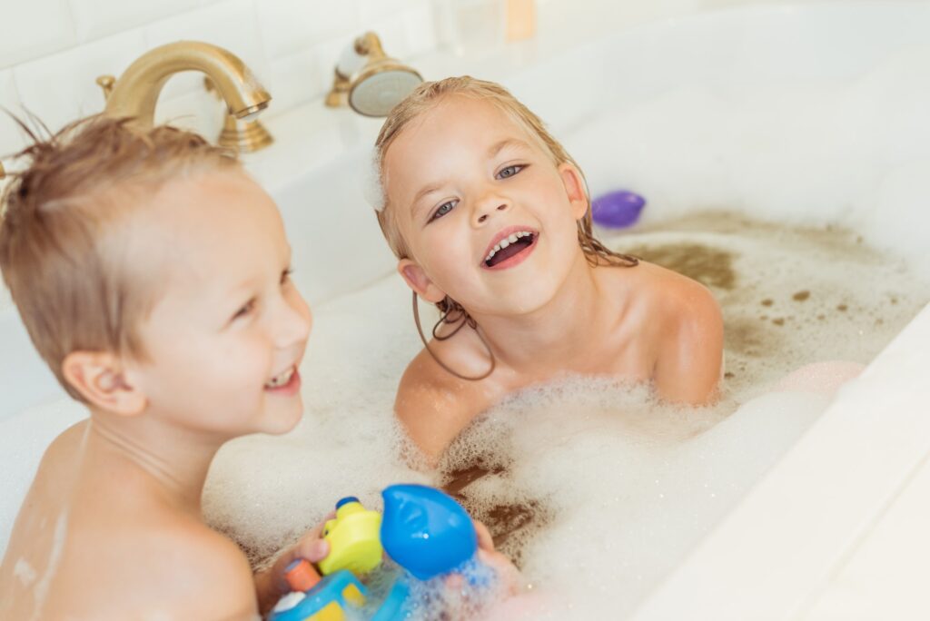 happy little brother and sister playing together in bathtub
