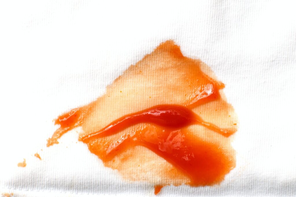 Tomatoes and ketchup stain on white shirt clothes close up