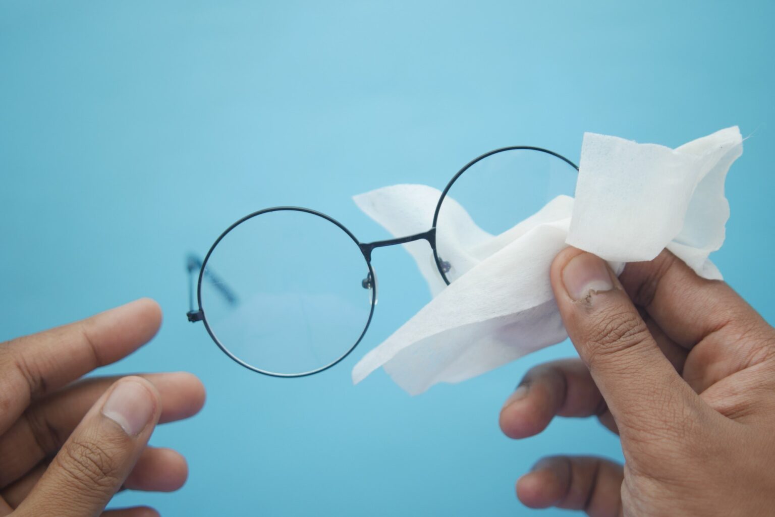 cleaning eyeglass with tissue close up