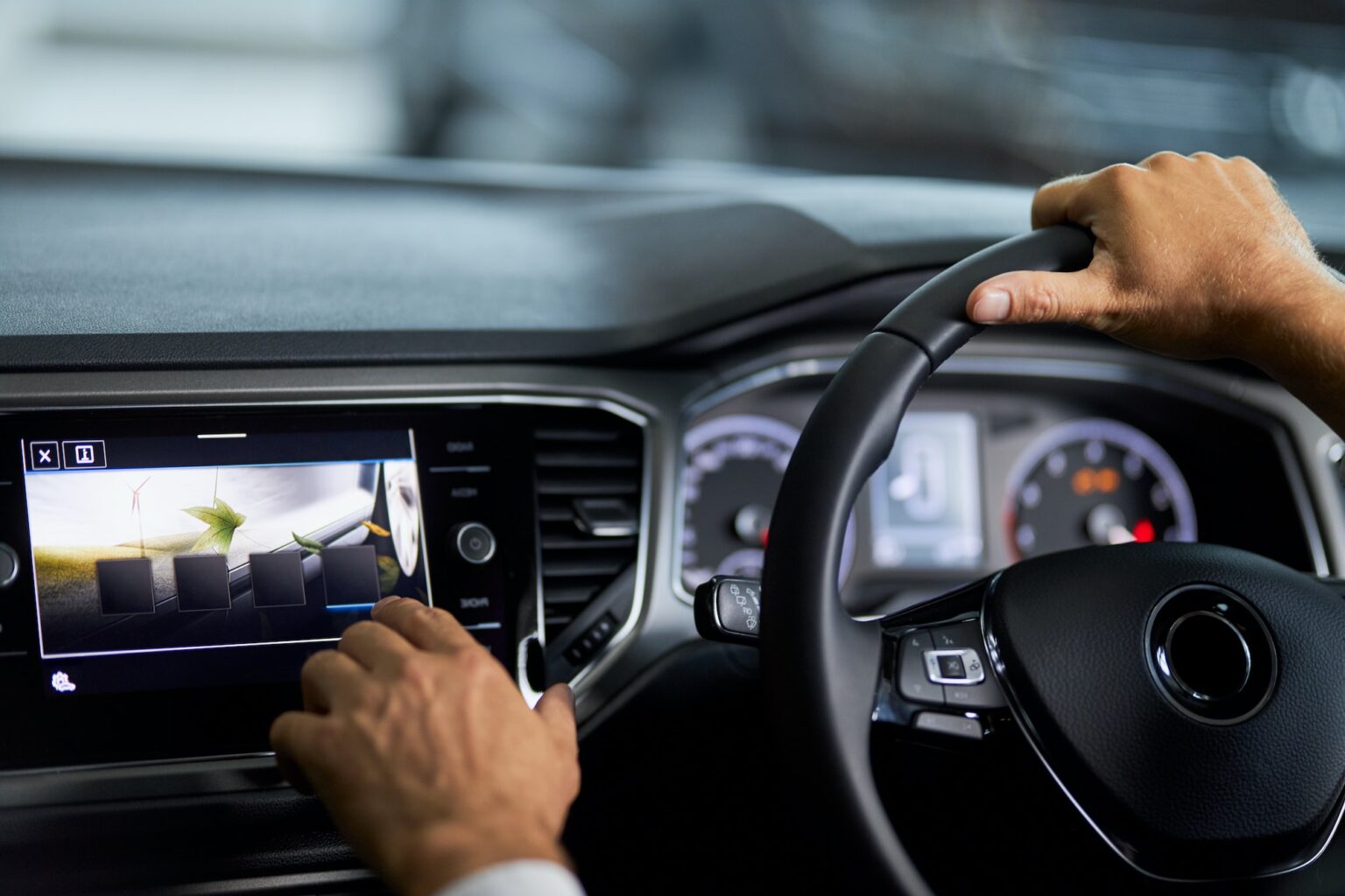 Man sitting in car and touching digital display of dashboard