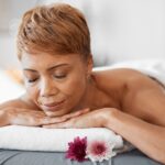 Peace, wellness and black woman at spa sleeping on cosmetology salon bed for relaxing back treatmen