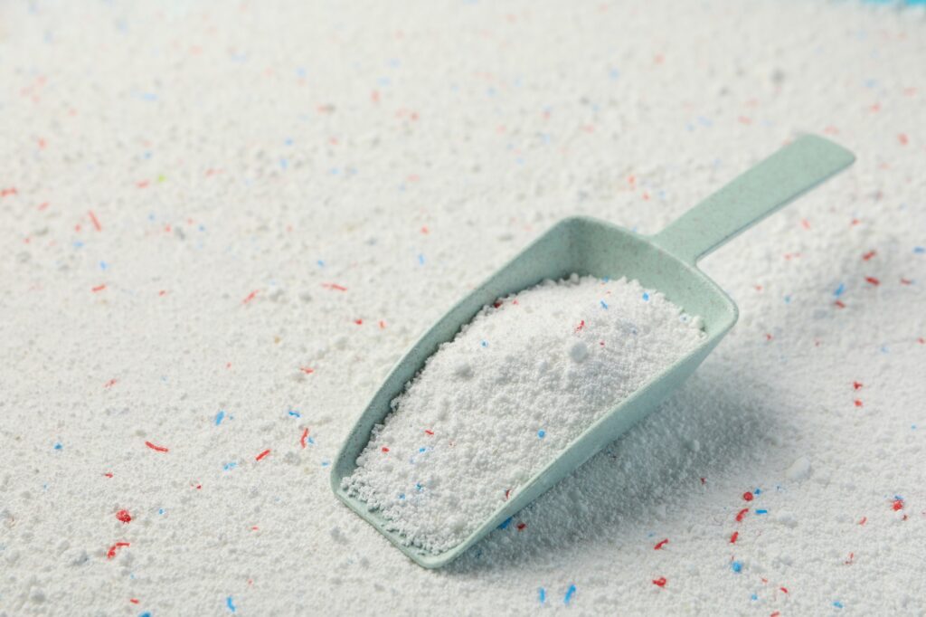 Scoop with washing powder on washing powder background