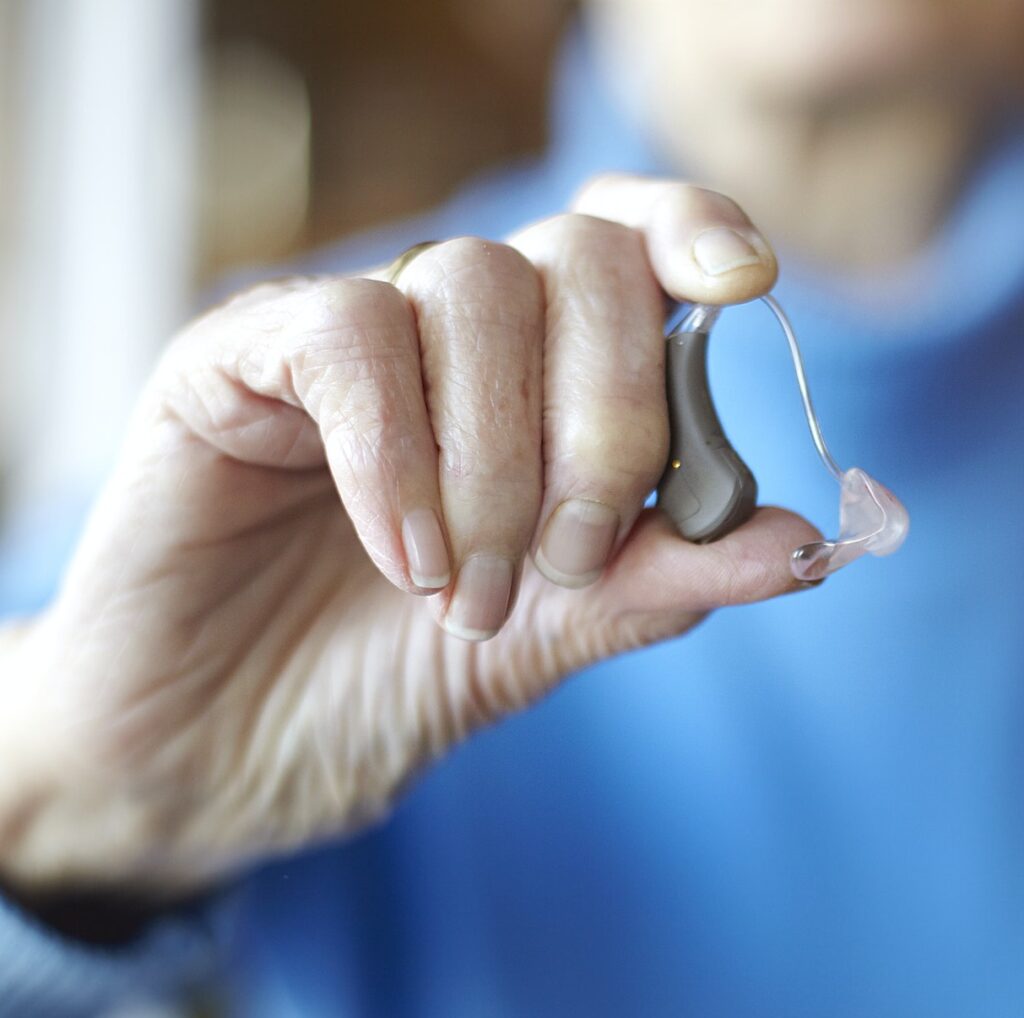 Senior woman holding hearing aid, close-up