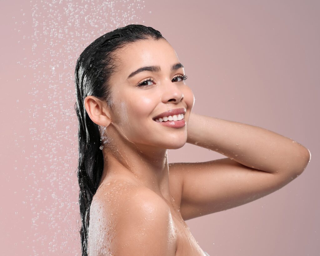 Shot of a young woman rinsing her hair against a studio background